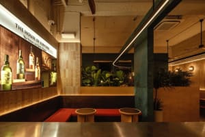 Modern restaurant interior with red benches, potted plants, and a welcoming atmosphere