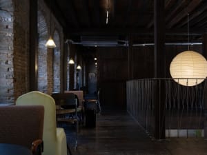 Cozy restaurant interior with wooden floors and walls, featuring chairs, tables, a dining table, and a couch