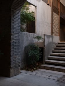 A building with a traditional design featuring concrete staircase, stairs on both sides, and a doorway