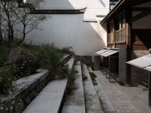 A serene building with a stone exterior, two wooden benches, and a peaceful atmosphere