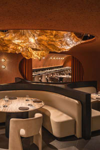 A warm and inviting restaurant dining area with tables and chairs arranged throughout the space, creating a comfortable atmosphere for guests