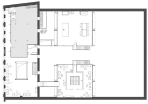 A dimly lit interior space with a mix of rooms, including a dining area and living room, featuring concrete walls, hardwood flooring, and cozy lighting