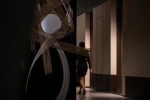 A woman walks down a hallway in an office building with a wooden floor and a door on one side, set in a professional environment