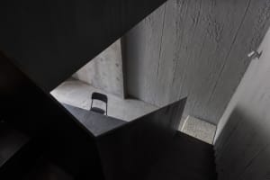 A photo of a staircase with a black metal railing and a chair on one step, in a building with a modern atmosphere