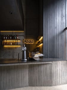A modern bar area with a glass countertop featuring various bottles and a cup, set in a well-designed establishment