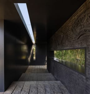 Interior design featuring a black wall and a large window with two smaller windows, allowing natural light into the space