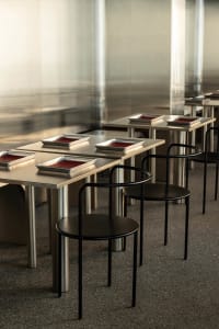 Industrial kitchen with multiple dining tables, stainless steel surfaces, and overhead lighting