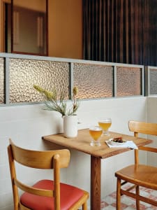casual dining space with a wooden table, two chairs, wine glasses, and a vase with flowers