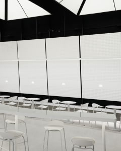 A modern restaurant interior with white walls, dining tables, and chairs, creating a clean and inviting atmosphere