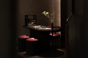 A small kitchen area with a dining table surrounded by chairs, featuring a vase and two cups, creating a cozy and inviting atmosphere