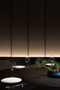 Sophisticated dining area with a round table set for a meal, featuring multiple wine glasses, plates, and bowls