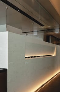 A modern kitchen with a white marble countertop, two wine glasses, and warm lighting creating a luxurious and inviting atmosphere