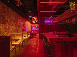 A restaurant interior with red walls, wooden furniture, and dining tables, creating a warm and inviting atmosphere for socializing and dining