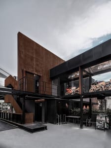 A black boat-shaped building with a large window and several chairs and motorcycles inside