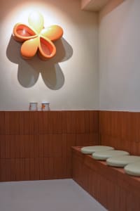 A warm and inviting cafe interior with ceramic flower decorations on a wall, adding a pop of orange color to the space