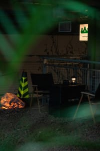 A relaxed outdoor patio with two chairs, a fire pit, and two dining tables, perfect for socializing and enjoying meals