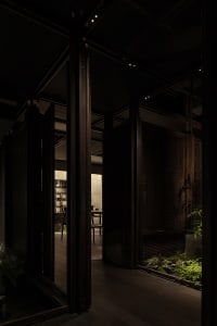Warm and inviting living and dining area with wooden floors and walls, featuring a dining table, chairs, and a potted plant