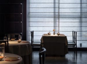 Empty restaurant dining area with wooden tables and chairs, wine glasses on some tables, inviting atmosphere