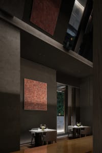 Elegant dining space with marble surfaces, tables, chairs, and wine glasses, highlighted by warm lighting
