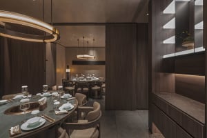 Empty restaurant with wooden floors and walls, featuring dining tables with white tablecloths and chairs