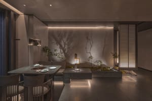 Empty modern living room with grey stone flooring, two dining tables, chairs, and potted plants, featuring a clean and minimalist design