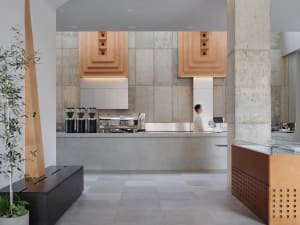 Industrial kitchen with concrete walls and floors, featuring multiple sinks, appliances, and cups, with a focus on functionality and organization