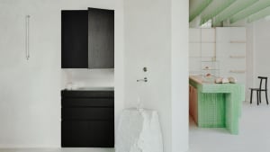 A white kitchen with a black cabinet and open drawer, featuring two bottles on the countertop in a clean and organized space