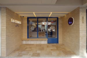 A restaurant interior with a wooden theme, featuring a large window, bench seating, and natural light