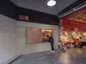 A casual coffee shop interior with a brick-patterned wall, chairs, and a counter, creating a welcoming atmosphere