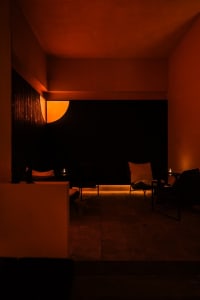 Cozy restaurant space with an orange-lit room, black walls, and a dining table with chairs and decorative items