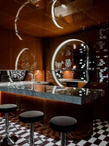 Elegant kitchen with a marble island, stools, wine glasses, and a sink, set in a modern and sophisticated atmosphere