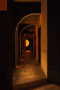 A calm and inviting indoor hallway with a black and white color scheme, featuring a large archway and smooth concrete-like walls