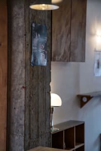 Cozy living and dining space with a wooden wall, lamp, posters, and a dining table