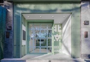 Modern entrance with green walls, a glass door, and two rooms visible through the doorway, one with a window and the other empty