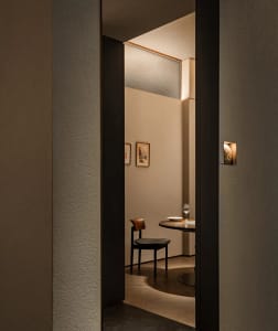 A modern dining area with a concrete finish, featuring a table and two chairs in a dimly lit space