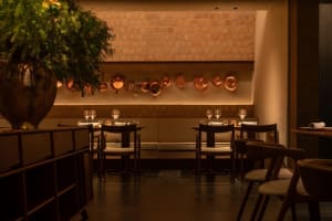 Sophisticated dining space with wooden tables, chairs, and wine glasses, set in a warm and inviting atmosphere