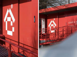 A modern building with a red wall and white door, made of concrete, with clean lines and minimalistic design elements, well-lit and welcoming