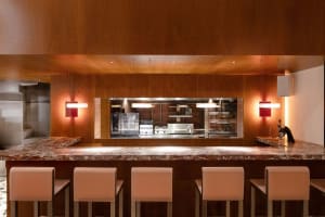 Warm and inviting restaurant kitchen with wooden walls and floors, a marble bar, and various appliances
