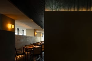 Spacious dining area with modern tables and chairs in a dimly lit restaurant with a minimalist aesthetic