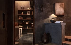 Dark hallway with a doorway, bookshelf, and decorative vase, possibly lacking natural light