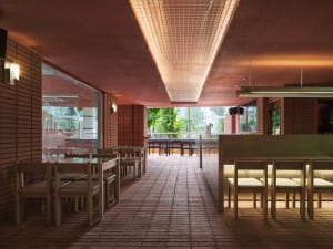 A well-lit restaurant with brick walls, red ceiling, and dining tables and chairs, creating a warm and inviting atmosphere