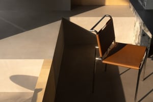 A leather chair sits on a hardwood floor in front of a wall, creating a comfortable and inviting atmosphere