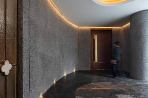 A luxurious hotel hallway with a marble floor and walls, lit by lights on both sides, creating an elegant atmosphere