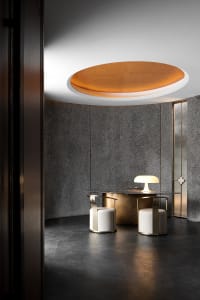 Dimly lit office space with grey walls, a circular ceiling light, and two chairs in front of a desk