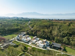 A picturesque village of wooden houses situated on a hillside surrounded by mountains and trees, creating a peaceful and serene environment