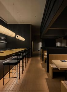 Dimly lit restaurant with wooden floors, modern design, and minimalistic decorations