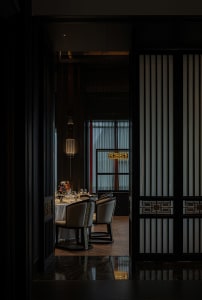 Sophisticated dining area with a large wooden table, multiple chairs, and wine glasses, set in a warm and inviting atmosphere