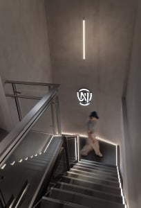 A man walks down a modern metal staircase with a glass railing in a building with a sense of movement and activity