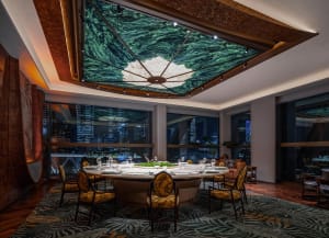 A warm and inviting restaurant dining area with a wooden table and yellow fabric chairs, surrounded by a tree canopy ceiling