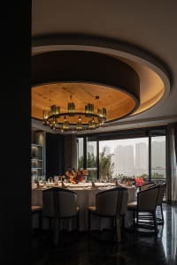 Sophisticated dining space with a round table, wine glasses, and wood and metal elements, set against a refined backdrop